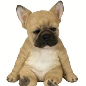 Puede incluir: Una figurita de cachorro de bulldog francés de color marrón claro y blanco, sentada con las piernas cruzadas. La figurita está hecha de poliresina y tiene un aspecto realista.