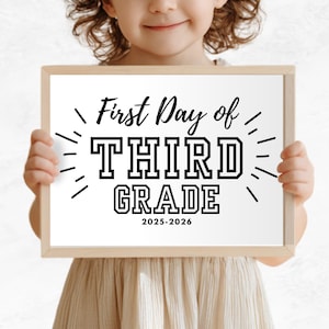 May include: A child holds a wooden framed sign that reads "First Day of THIRD GRADE 2025-2026" in black text. The sign has a white background and is surrounded by decorative lines. The child is wearing a beige dress.