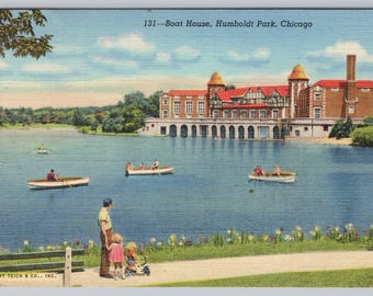 May include: Vintage postcard of the Boat House in Humboldt Park, Chicago. The image shows a large brick building with a red roof and several small boats on the lake. A family stands on the shore.