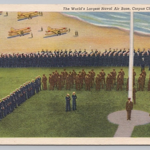 May include: Vintage postcard depicting The World's Largest Naval Air Base in Corpus Christi, Texas. The image shows a large gathering of military personnel, aircraft, and an American flag. The scene is set on a grassy field and beach.