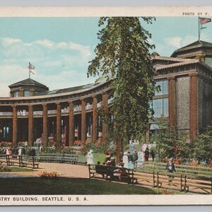 May include: A white ceramic mug with a black handle and the text "But First, Coffee" in a black, handwritten-style font. The mug is on a white surface.