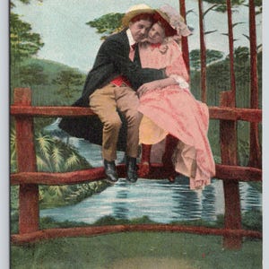 May include: A vintage postcard illustration depicts two figures sitting on a wooden fence over a stream. The text reads: How are you and the Edilens Girls making it? I've got a very steady job. Copyright 1908, by Bamforth & Co.