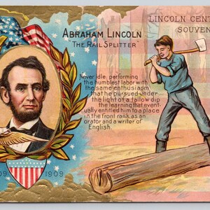 May include: A vintage postcard titled Lincoln Centennial Souvenir featuring a portrait of Abraham Lincoln in a gold laurel wreath, an American flag, and an illustration of a person splitting a log with an axe, with text detailing his life.