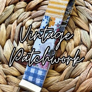 May include: A fabric keychain with a patchwork design. The keychain features sections of yellow and white stripes, floral patterns, and blue gingham. The words "Vintage Patchwork" are written across the front. A silver-colored metal ring is attached.