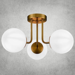 May include: A gold ceiling light fixture with three white globe-shaped shades. The fixture has a modern design with curved arms.