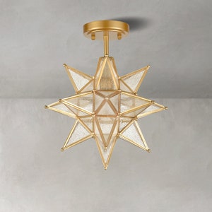 May include: Gold ceiling light fixture shaped like a star with clear glass panels.