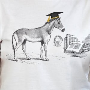 May include: A black and white illustration of a donkey wearing a graduation cap and looking at a stack of books. The donkey is standing on a grassy surface with a globe in the background.