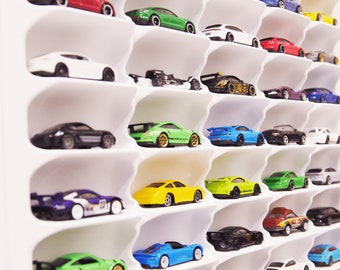 May include: A white shelf unit with multiple slots displays a collection of miniature toy cars in various colors, including red, green, blue, yellow, black, and white.