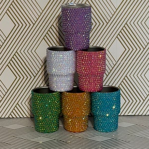 May include: Six stainless steel tumblers with a variety of colours and rhinestones. The tumblers are arranged in a pyramid shape.