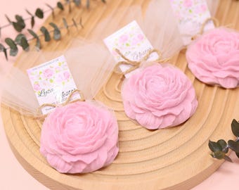 May include: Three pink rose-shaped soaps wrapped in sheer white tulle fabric, each tied with a brown twine bow and a small rectangular tag featuring floral illustrations and the text "THE ENGAGEMENT OF Lyza and Nestor 05.20.2024".