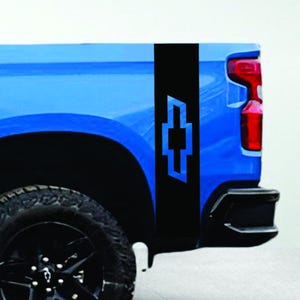 May include: A blue pickup truck with a black stripe and a blue Chevrolet logo on the side. The truck has black tires and a black wheel. The truck bed is visible.
