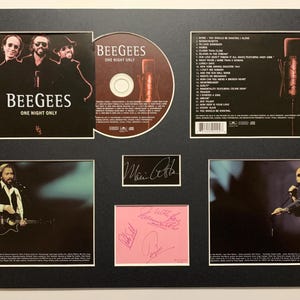 Puede incluir: Exhibición enmarcada con CD y portada del álbum "One Night Only" de los Bee Gees. Incluye imágenes de los miembros de la banda, una lista de canciones y firmas. La exhibición está sobre un fondo negro.