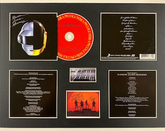 May include: Framed Daft Punk "Random Access Memories" album art, CD, and signed photo. The album cover features a silver and gold helmet. The CD is red with "Columbia" branding. The signed photo shows the band's silhouette.