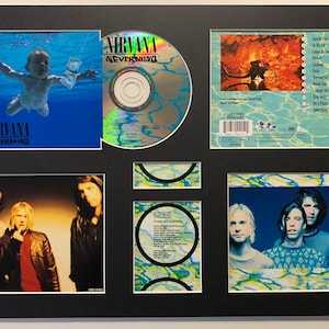 May include: A framed Nirvana "Nevermind" CD and album art display. The display includes the album cover with a baby in water, the CD, and images of the band members. The album title is visible.