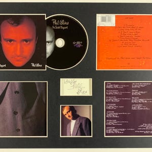 Peut inclure: Un ensemble encadré de souvenirs de Phil Collins, comprenant un CD, une pochette d'album et un autographe signé. La pochette de l'album présente un gros plan du visage de Phil Collins avec le titre de l'album "No Jacket Required". Le CD est noir avec du texte blanc.
