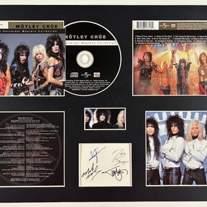 May include: A framed Motley Crue Universal Masters Collection CD set. The set includes a CD, album art, band photos, and a signed autograph. The album art features the band members in various poses, with the album title prominently displayed.