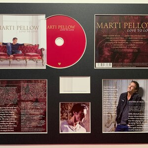 Puede incluir: Un CD enmarcado con un fondo rojo y el texto "Marti Pellow Love to Love" en la parte delantera. La parte posterior del CD presenta una lista de canciones, que incluyen "Don't Know Much", "After the Love Has Gone", "You Are So Beautiful", "Baby Come to Me", "Never Told Only You", "Suddenly", "Caught Up in the Rapture", "I Surrender", "I'll Be Over You" y "Angel".