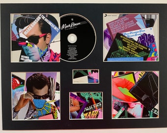 Può includere: Un collage incorniciato di copertine di album colorate e un CD con Mark Ronson e il testo "The Business Intl." e "Record Collection".