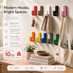 May include: A set of ten J-shaped wall hooks in various colors including red, brown, white, black, pink, orange, yellow, blue, grey, and green. The hooks feature a ribbed texture and are mounted on a wall, holding items like keys and a towel.