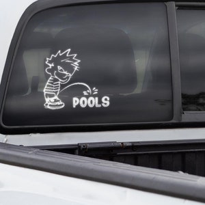 Puede incluir: Camioneta blanca con una caja negra y una pegatina en la ventana trasera de un personaje de dibujos animados haciendo pis con el texto "POOLS" debajo.