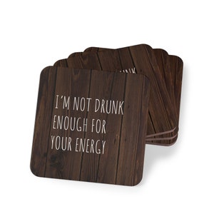 May include: Set of four brown wooden coasters with a white inscription that reads "I'm not drunk enough for your energy".