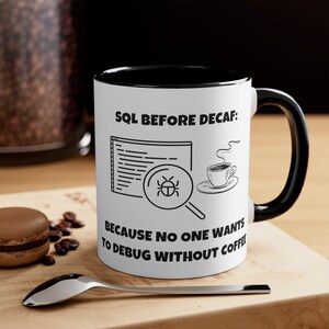 May include: White coffee mug with a black rim and handle. The mug has a black and white illustration of a computer screen with code and a magnifying glass with a bug inside. The text on the mug reads "SQL Before Decaf: Because no one wants to debug without coffee."