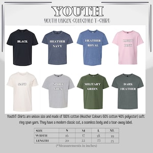 Pu&ograve; includere: Esposizione di t-shirt unisex softstyle per ragazzi in vari colori, tra cui nero, blu navy m&eacute;lange, blu royal m&eacute;lange, rosa chiaro, sabbia, grigio sport, verde militare e m&eacute;lange scuro. Ogni maglietta ha il nome del colore stampato. Tabella delle taglie in pollici.