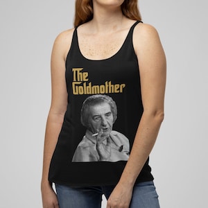 May include: Black tank top with a gold graphic that says "The Goldmother" and a black and white photo of a person smoking a cigarette.