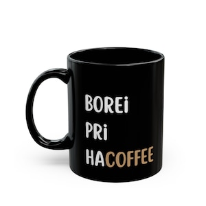 May include: Black coffee mug with white text that reads "Borei Pri Hacoffee" in a stacked format. The word "Hacoffee" is in a brown color.