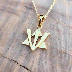 A gold-colored pendant necklace with a Star of David design is displayed on a wooden surface.