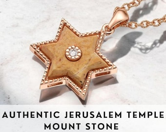May include: A gold pendant necklace featuring a six-pointed star with a light brown stone in the center. The stone is surrounded by a small diamond. The pendant is on a delicate gold chain. "AUTHENTIC JERUSALEM TEMPLE MOUNT STONE" is written below the pendant.