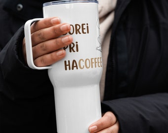 May include: White stainless steel travel mug with a black handle. The mug has the text "Morei Pri Hacoffee" printed on it in brown lettering.