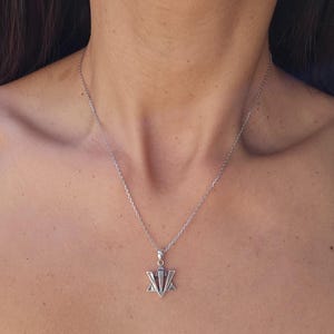 A silver necklace with a pendant is shown in the image.