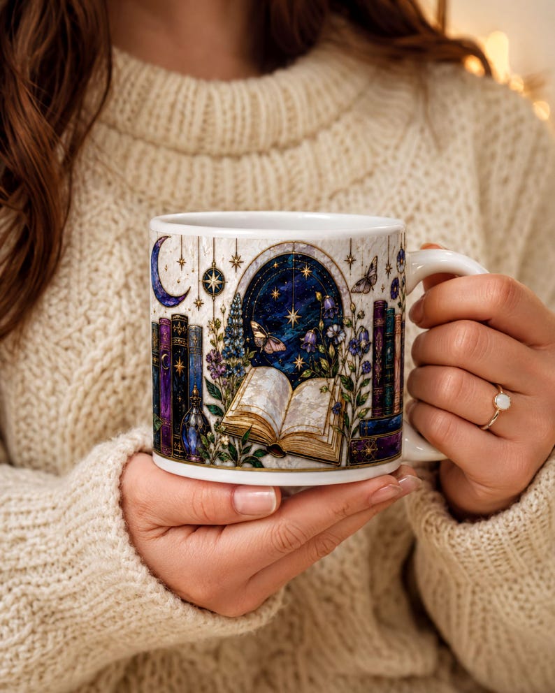 A person is holding a mug with a night sky and stars design, featuring a book and other celestial elements.