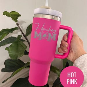 Engraved Hockey Mom tumbler with hockey stick and heart design; stainless steel insulated travel cup with handle; personalized drinkware for sports moms; custom cup for hockey games, practices, or gifts; durable large-capacity tumbler perfect for birthdays, holidays, and hockey season celebrations; stylish engraved design for everyday use.