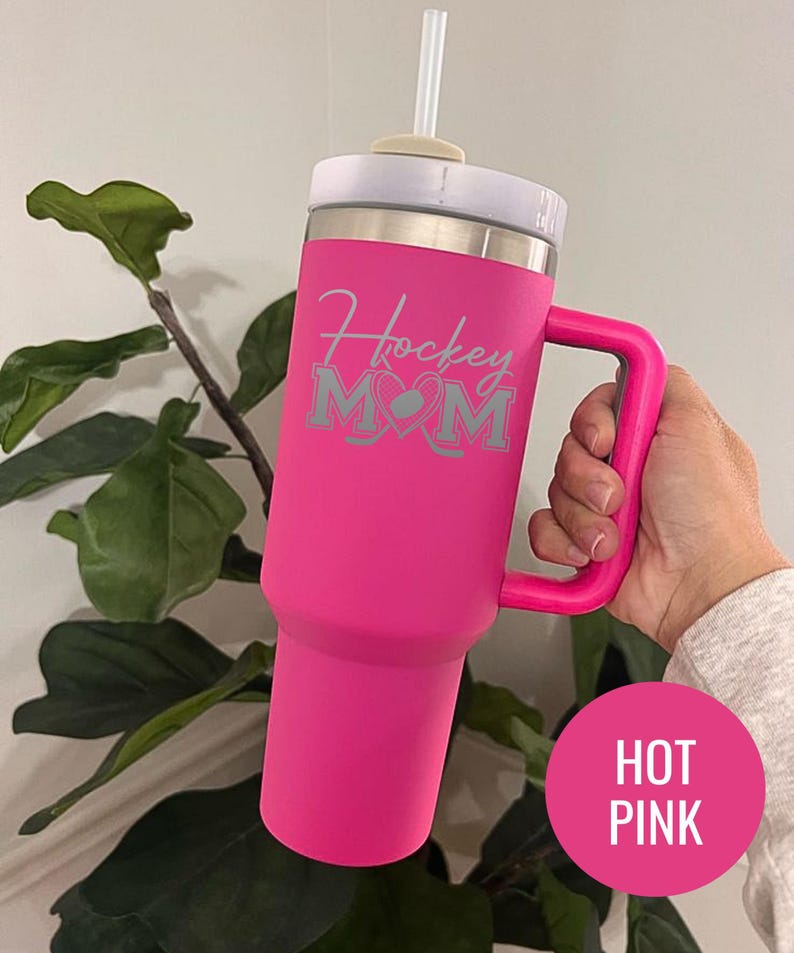 Engraved Hockey Mom tumbler with hockey stick and heart design; stainless steel insulated travel cup with handle; personalized drinkware for sports moms; custom cup for hockey games, practices, or gifts; durable large-capacity tumbler perfect for birthdays, holidays, and hockey season celebrations; stylish engraved design for everyday use.