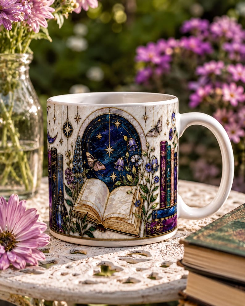 A white ceramic mug with a detailed illustration of a book, flowers, and a starry night sky, placed on a lace tablecloth.
