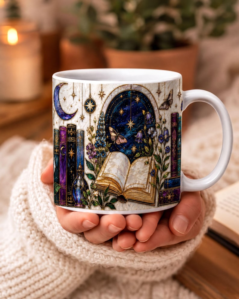 A person's hand holding a white mug with a colorful, whimsical design featuring books, plants, and a starry night sky.