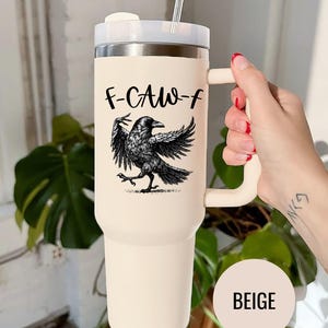 A stainless steel insulated tumbler featuring a detailed black raven illustration with wings spread, paired with the phrase "F-Caw-F" in playful script; the design blends gothic and humorous elements, creating a unique travel cup for bird enthusiasts, crow lovers, or fans of dark sarcastic quotes; shown on tumblers in various matte finishes, each with a handle and straw for practical everyday use.