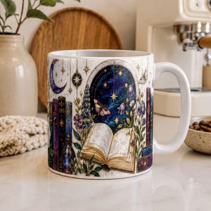 A white ceramic mug with a colorful, illustrated design depicting a night sky, stars, a crescent moon, a book, and various plants and flowers.