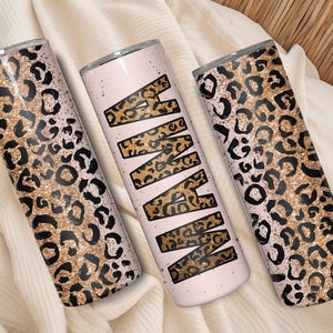 May include: Three stainless steel tumblers with a leopard print design. One tumbler has the word "MAMA" in a leopard print pattern. The other two tumblers have a gold glitter and black leopard print pattern.