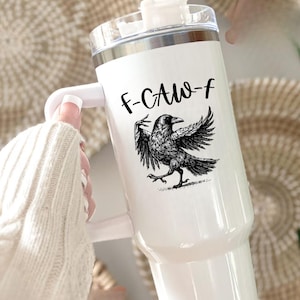 A stainless steel insulated tumbler featuring a detailed black raven illustration with wings spread, paired with the phrase "F-Caw-F" in playful script; the design blends gothic and humorous elements, creating a unique travel cup for bird enthusiasts, crow lovers, or fans of dark sarcastic quotes; shown on tumblers in various matte finishes, each with a handle and straw for practical everyday use.