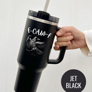 A stainless steel insulated tumbler featuring a detailed black raven illustration with wings spread, paired with the phrase "F-Caw-F" in playful script; the design blends gothic and humorous elements, creating a unique travel cup for bird enthusiasts, crow lovers, or fans of dark sarcastic quotes; shown on tumblers in various matte finishes, each with a handle and straw for practical everyday use.