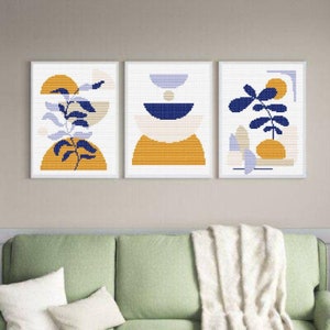 Puede incluir: Tres impresiones enmarcadas con diseños geométricos abstractos en tonos de amarillo, azul y blanco. Las impresiones presentan motivos vegetales estilizados y formas geométricas.