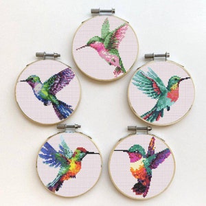 May include: Five embroidery hoops with colorful hummingbird designs. Each hoop features a different hummingbird with vibrant colors and intricate details. The hoops are perfect for adding a touch of nature to any room.