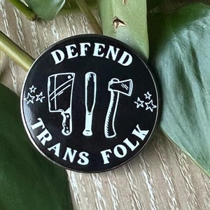 rund svartvit nålknapp "försvara transpersoner"