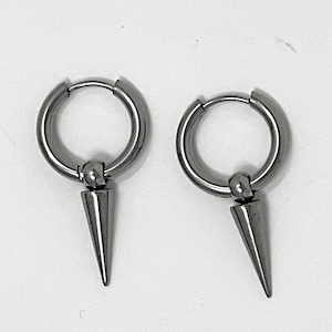 Peut inclure: Une paire de boucles d'oreilles créoles argentées avec un pendant conique et pointu. Les boucles d'oreilles ont un design simple et moderne, avec une finition polie. Les créoles sont rondes et les pendants sont en forme de cône.