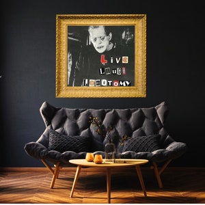 May include: A framed black and white photo of a man with a serious expression. The photo is in a gold frame and has the words "Live Laugh Lobotomy" written on it in red, black, and white letters.