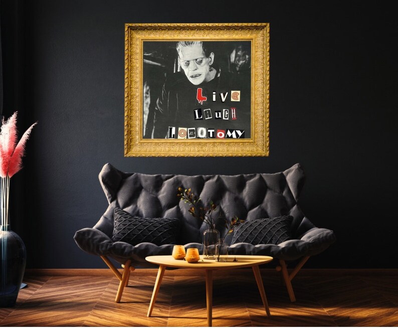 May include: A framed black and white photo of a man with a serious expression. The photo is in a gold frame and has the words "Live Laugh Lobotomy" written on it in red, black, and white letters.