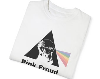 May include: White t-shirt with a black triangle graphic featuring a silhouette of Sigmund Freud with a rainbow prism behind him. The text "Pink Freud" is printed below the triangle.